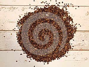 A pile of organic buckwheat husks used as a filling for buckwheat pillow on a wooden planks background