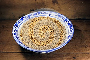 Pile of organic whole grain wheat. Fresh harvested wheat grain in a bowl isolated on wooden background.