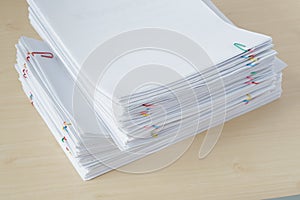 Pile of overload paper and reports with colorful paper clip