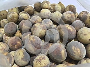 A pile of overripe duku fruit in plastic