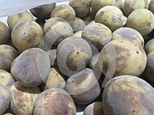 A pile of overripe duku fruit in plastic