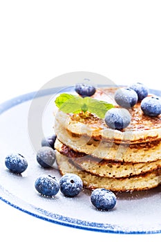 Pile of pancakes with blueberries sprinkled with icing sugar