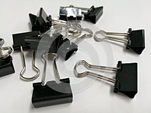 Pile of paper clip and fold black clip on white background. and close up stationery object