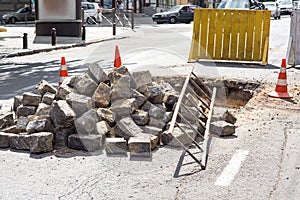 Pile of paving stones dug out of a hole under asphalt in the process of repairing the road.