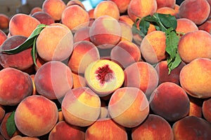 A pile of peaches and one peach, cut in half