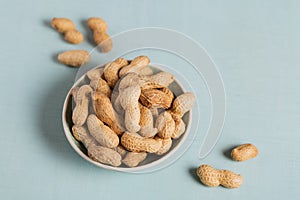 Pile of Peanuts in a bowl on a light blue background