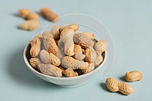 Pile of Peanuts in a bowl on a light blue background