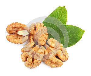 Pile of peeled walnuts and leaves on white background, top view