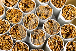 A pile, a pile of cigarettes in front of tobacco, a stack as a background texture, close-up, in front.