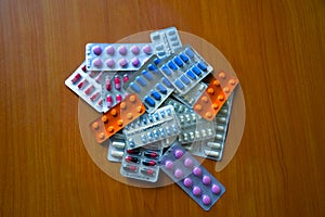 A pile of pills in blister packs. Blister packs full of multi-colored pills. Close up on wooden background.