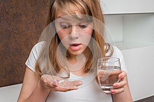 Pile of pills and glass of water in female hands