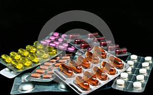 Pile of pills and vitamins in blister packs on dark background with copy space. Medical pharmacy concept