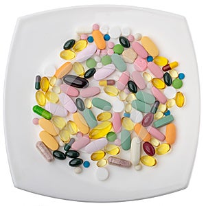 A pile of pills on a white plate symbolizing food. Vitamins on a white isolated background. Pink pills and burgundy