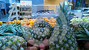 Pile of pineapple, orange and fresh exotic fruit on a supermarket. Blur market background. Ananas. Retail industry. Grocery