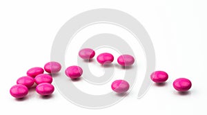 Pile of pink round sugar coated tablets pills isolated on white background with copy space.