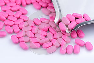 Pile of pink tablets pill on white background near stainless steel drug tray. Norfloxacin 400 mg for treatment cystitis. photo