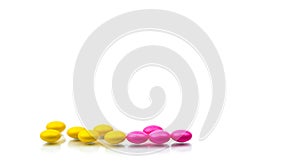 Pile of pink and yellow round sugar coated tablets pills isolated on white background with copy space. Colorful pills