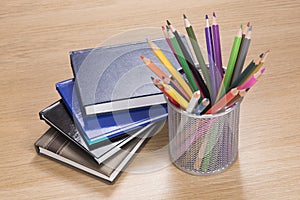 Pile of planners with colored pencils in stand