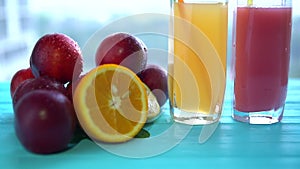 Pile of plums and citrus fruit next to two glasses