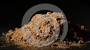 Pile powder cinnamon rotating in black background