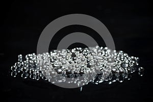 A pile of pure silver granules. Isolated on mirror black background.