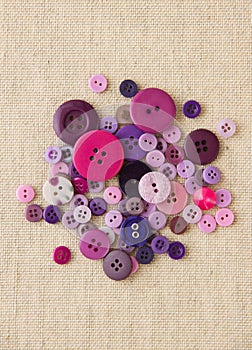 Pile of purple buttons on hessian