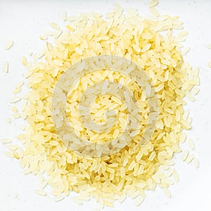 Pile of raw parboiled rice close up on gray