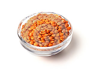 A pile of raw red lentils in a glass container, isolated on a white background. useful product