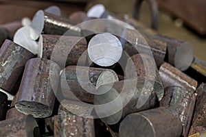 A pile of raw steel short rods cutted by saw- workpieces prepaired for forging, close-up with selective focus
