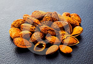 Pile of raw unpeeled almond on grey surface