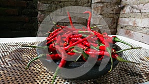 Pile of red chilies on a mortar with a blurred brick wall