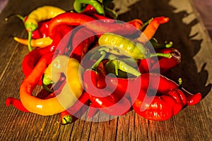 a pile of red and green hot peppers on a wooden table