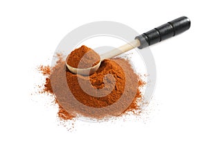 Pile of red ground paprika with wooden spoon on white