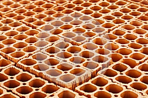Pile of red hollow bricks with large holes forming a repetition geometric pattern