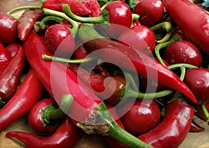 Pile red hot peppers on wooden table close up. Hot peppers background. Cherry peppers and Italian Long Hots photo