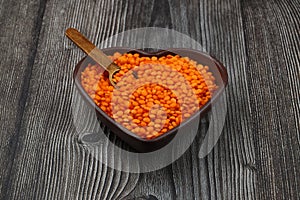 Pile red lentil in shape of heart isolated on wooden background. Top view. Flat lay.
