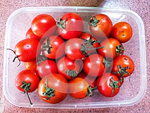 A pile of red tomatoes is on a tray