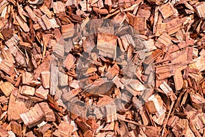 Pile of red wood chips for garden and landscape decoration, outdoors. Textured wood background