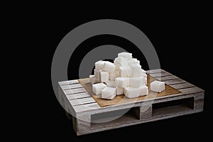 Pile of refined sugar cubes on wooden plate