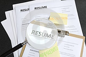Pile of resume templates and sticks on it, black background. HR made decision and approved one candidate and rejected to another.P