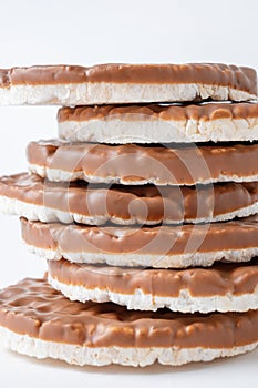 Pile of rice crispbreads coated with chocolate on white background close-up