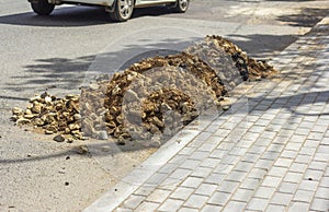 A pile of rocks and sand on the side of the road. Preparation for the repair of the road surface