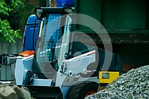 A pile of rubble and soil in the foreground. in the background a mini bulldozer loader