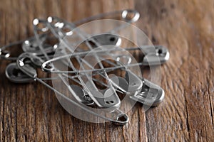 Pile of safety pins on wooden table, closeup