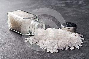 Pile of salt and salt shaker on black stone background
