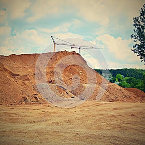 Pile of sand and construction of new homes. Concept for industry. Crane and blue sky with clouds and sun. Building construction si