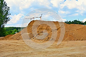 Pile of sand and construction of new homes. Concept for industry. Crane and blue sky with clouds and sun. Building construction si