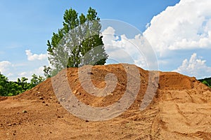 Pile of sand and construction of new homes. Concept for industry. Crane and blue sky with clouds and sun. Building construction si photo