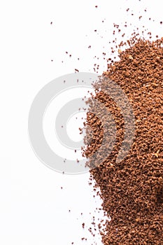 A pile of scattered ground coffee on a white background. The grains of ground black coffee are very close. Close up ground coffee