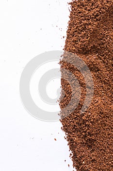 A pile of scattered ground coffee on a white background. The grains of ground black coffee are very close. Close up ground coffee